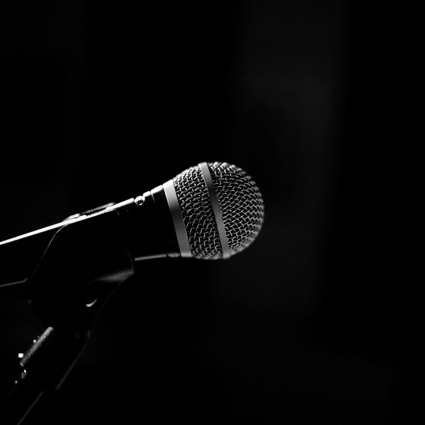 The microphone for the stage stands on a stand on a black background. Black and whire photography.